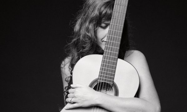 Mariel Martinez, cantante de tango en Madrid abrazando su guitarra